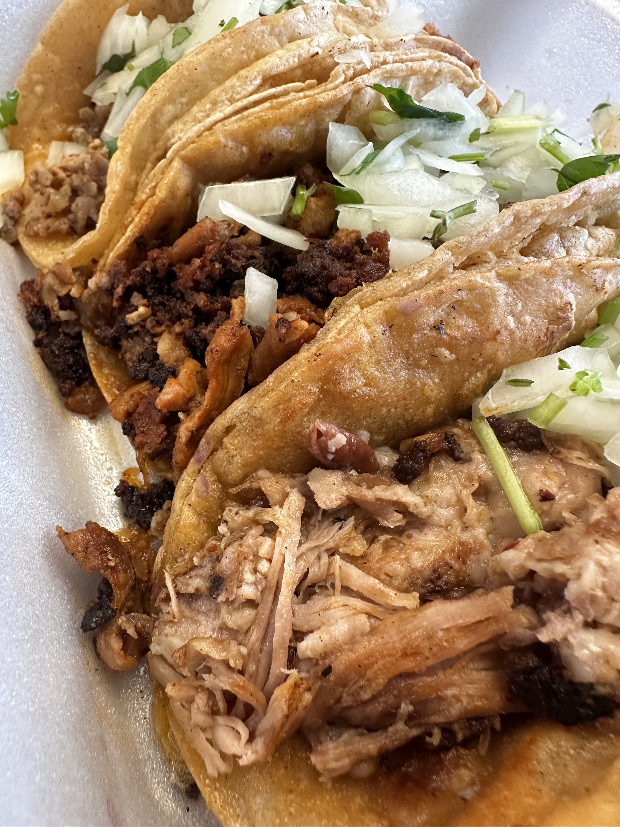 Three tacos loaded with meat and onion