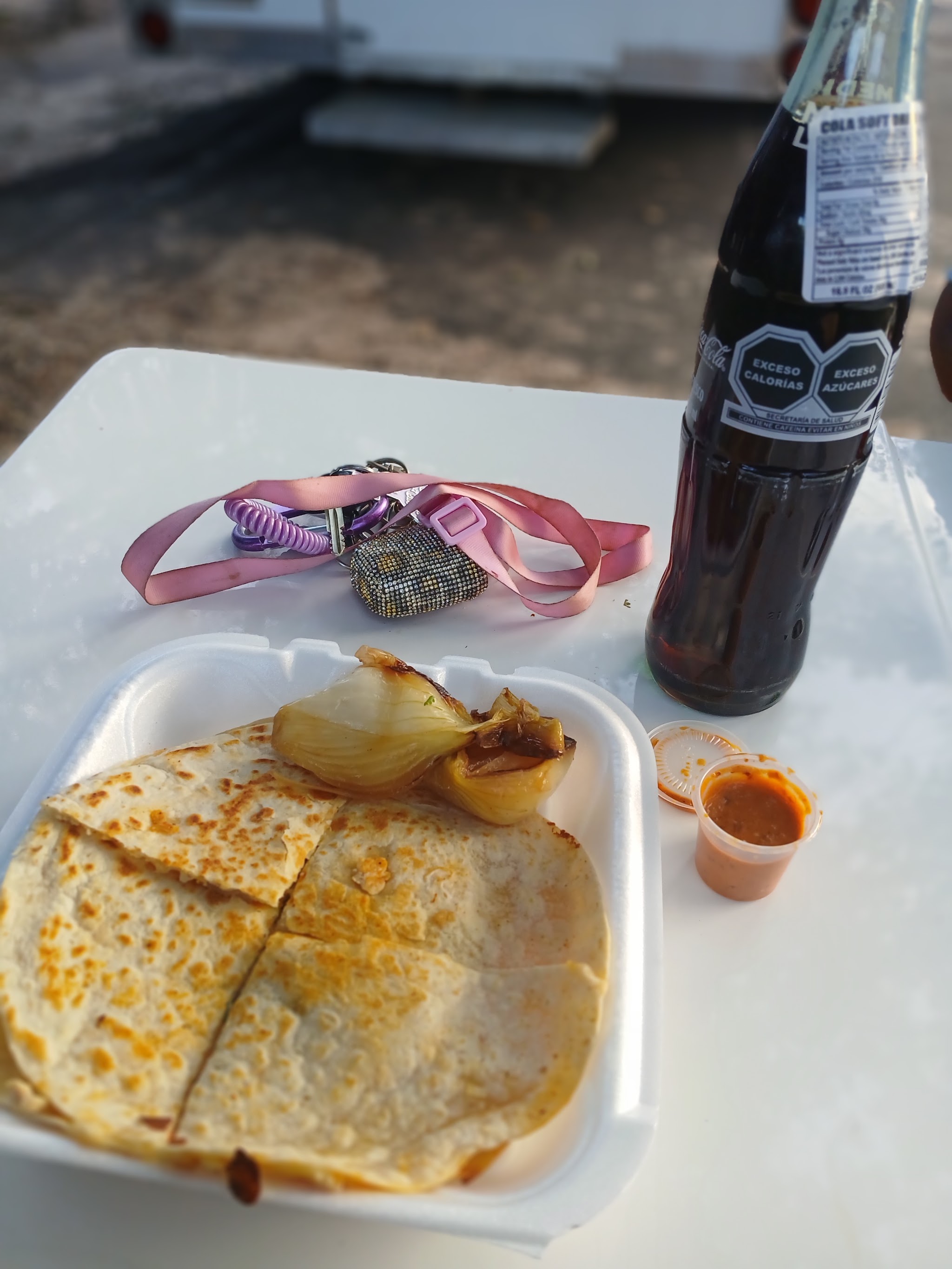 A quesadilla and a bottle of Mexican Coke on a table